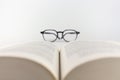 Close-up of an open book with reading glasses on a white background Royalty Free Stock Photo